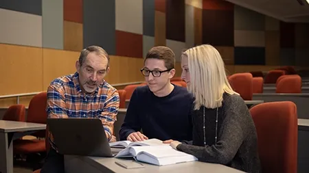 Students studying a text with a professor.